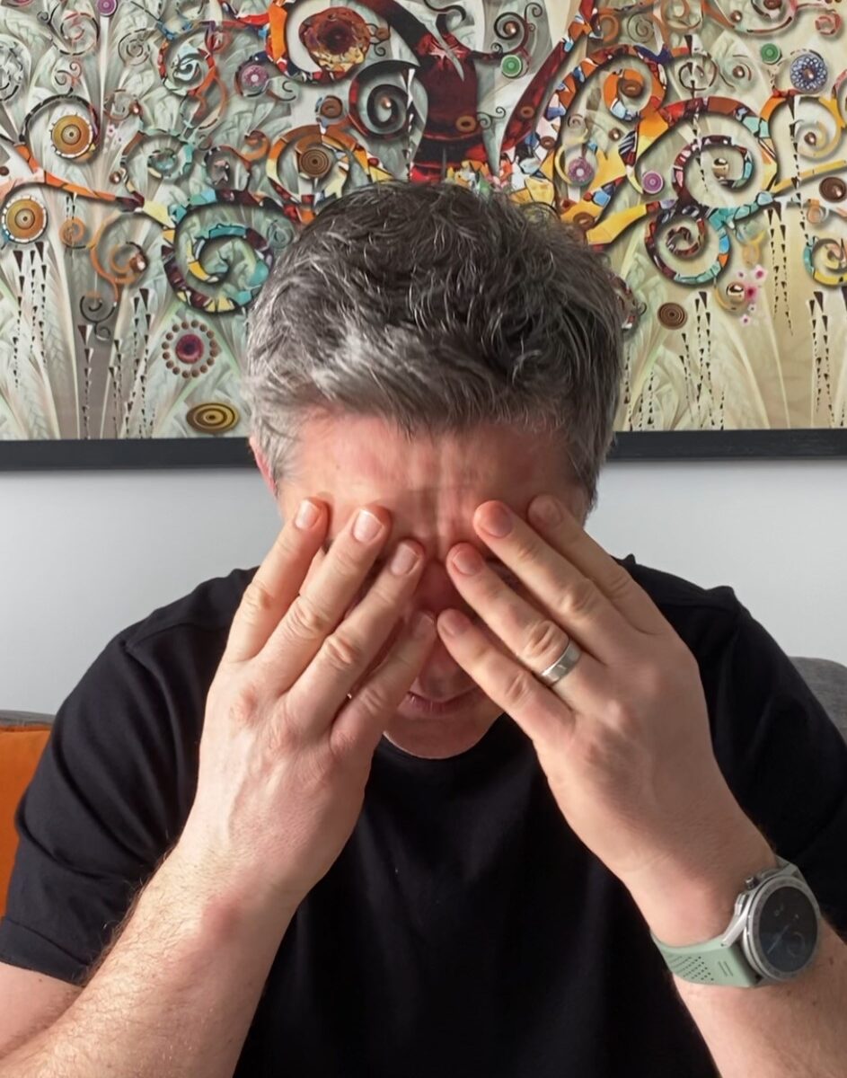 Man with head in hands showing visible emotional exhaustion